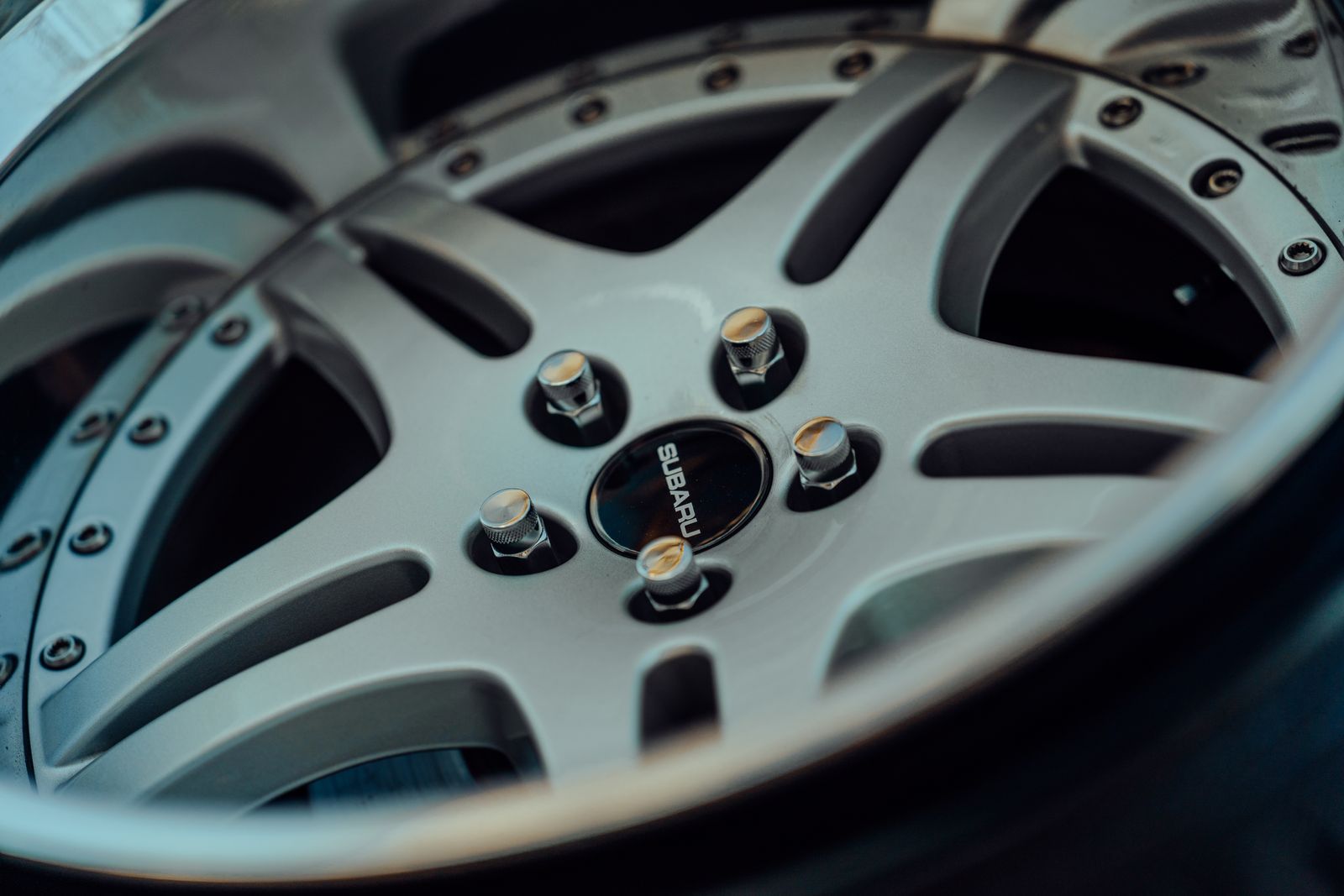 Detailed close-up of a silver alloy wheel with visible bolts, emphasizing design.